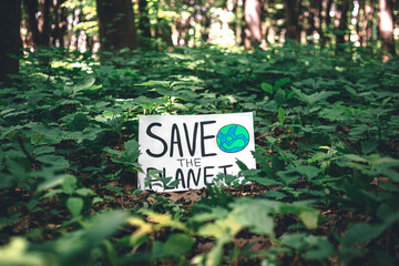 Wall Mural - Poster with the inscription save the planet in the forest among the plants.