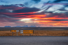 Directional Signboards With Text By Road. Information Signs On Roadside At Volcanic Landscape. Scenic View Of Land Against Dramatic Sky During Sunset.