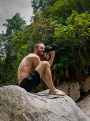 White Man Taking Pictures of the Nature Sitting in a Rock