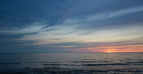 Wall Mural - Baltic sea at sunset. Dramatic sky, blue and pink glowing clouds, soft golden sunlight, midnight sun. Picturesque dreamlike seascape, cloudscape, nature. Panoramic view