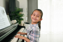 Cute Asian 6 Years Old Is Practice Playing Piano At Home And Smiling With Happiness Moment, Concept Of Learning, Art, Steam, Musical, Mental Health, Homeschool, Skill, Ability Concept.