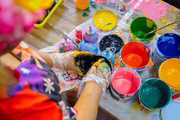 An art teacher is preparing different colors for the children. Kindergarten teacher and acrylic paint for kids