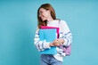 © gstockstudio - Cheerful female student carrying workbooks while standing against blue background