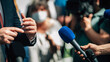 Media interview, a politician answering questions at a media press conference, reporter holding a microphone.