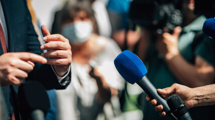 Wall Mural - Media interview, a politician answering questions at a media press conference, reporter holding a microphone.