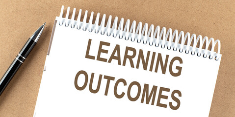 learning outcomes text on a notepad with pen, business concept