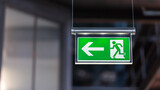 Fototapeta  - Illuminated emergency exit sign. Arrow pointing to the left.