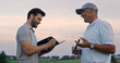 Two men talking golf course outside. Golfers analyze game result at sunset field