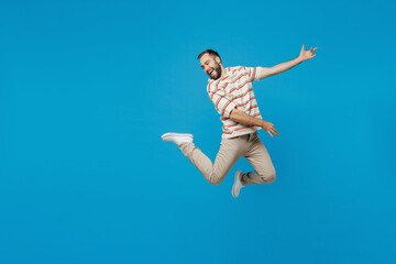 Wall Mural - Full body young expressive singer musician caucasian man 20s in orange striped t-shirt jump highdo playing guitar gesture isolated on plain blue background studio portrait. People lifestyle concept.