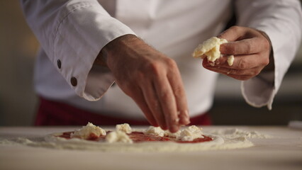 Pizza chef cooking meal in restaurant. Man hands put mozzarella cheese kitchen