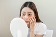 © KMPZZZ - Bored, insomnia asian young woman, girl looking at mirror, without makeup, touch under eyes with problem of dark circles, puffiness, swollen or wrinkles on face. Sleepless, sleepy people, copy space