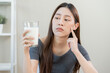Allergy asian young woman, girl looking, holding glass of milk, face in thinking before drink milk as it may upset her stomach ache, pain. Lactose intolerance and dairy food , health problem concept.