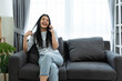 © Kawee - Asian beautiful woman sit on sofa and talk on mobile phone in house.