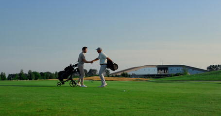 Wall Mural - Golf players meeting together on course field. Golfing team talking sport game.