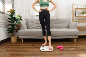 Healthy and weight loss concept, Young Asian woman stepping on weighing scales after weight control