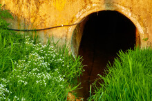 Small Stream Flows Through Circular Concrete Pipe. Electrical Cable On Wall.