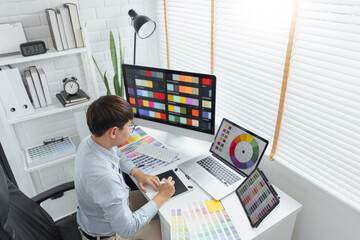 Creativity concept, Male graphic designer using tablet and looking color swatch samples on screen