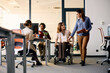 © Drazen - Happy businesswoman in wheelchair and her colleague talk while going through office.