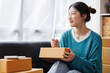 © David - Asian business woman on sofa using a laptop computer checking customer order online shipping boxes at home. Starting SME Small business entrepreneur freelance. Online business, SME Work home concept.