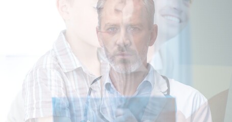 Double exposure of portrait of mature caucasian doctor and boy in hospital, copy space