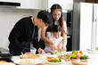 © SKW - Asian girl learning to cook with mom and dad. Do activities together with your family in a fun and joyful way. There is a father and mother taking care of them closely.