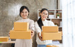 © Phushutter - Looking at camera,Partnership of SME entrepreneur teamwork of small business work at home family online marketing with packing box prepare for deliverty to customers at warehouse home seller office.