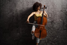 Young Female Artist Playing A Cello And Leaning On A Rusty Wall