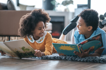 two kids lying on the floor and reading a book