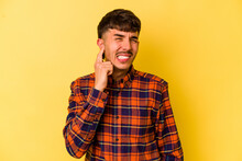 Young Caucasian Man Isolated On Yellow Background Covering Ears With Fingers, Stressed And Desperate By A Loudly Ambient.