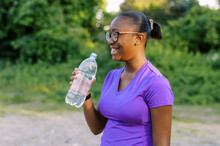 Smiling Teenage Girl With Glasses Drinking Water In Work Out Clothes