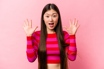 Wall Mural - Young Chinese woman isolated on pink background receiving a pleasant surprise, excited and raising hands.