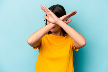 Wall Mural - Young caucasian woman isolated on blue background keeping two arms crossed, denial concept.