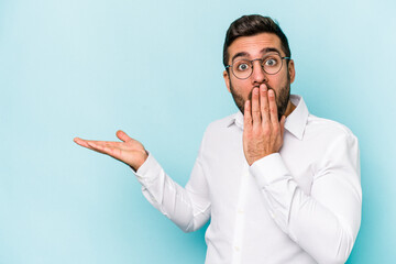 Wall Mural - Young caucasian man isolated on blue background impressed holding copy space on palm.