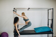 © Roman - pregnant woman pilates reformer cadillac exercise workout with personal trainer