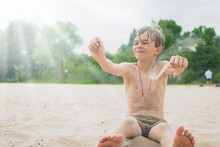 A Little Boy Plays In The Sand On The Beach