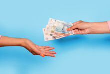 Hand Giving United Kingdom Pounds And Hand Take, Over Blue Background. Giving Money To Help