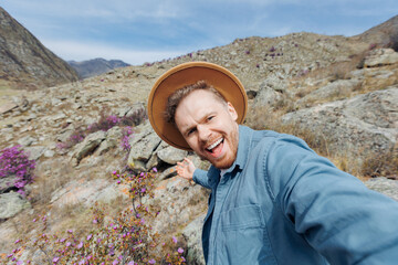 Wall Mural - Selfie photo Travel man in blooming flower pink maralnik of mountains Altai Siberia Russia trip