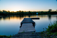 An Empty Dock Sits In The Still Water Of The Trent River During A Late Evening Sunset In Campbellford, Ontario.