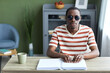 Front view portrait of adult black man reading tactile book in braille and wearing dark sunglasses, accessible education concept