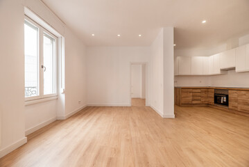 Poster - Newly renovated open plan kitchen with wood cabinets, wood counter tops with appliances, gloss white upper cabinets, plain white painted walls viewed from an empty living room