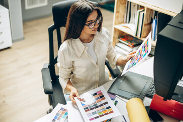 Wall Mural - Female digital designer looking at swatches at an office