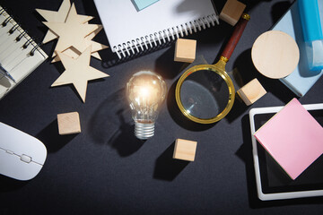 Wall Mural - Light bulb, wooden cubes, magnifying glass, wooden stars, notepad on the table.