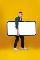 Poster - Man Carrying Huge Cellphone Empty Screen On Yellow Background, Vertical
