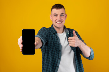 Poster - Cheerful Guy Showing Cellphone Gesturing Thumbs Up Over Yellow Background