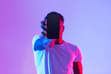 Poster - Young black guy holding cellphone with empty screen in front of his face, offering space for mockup in neon light