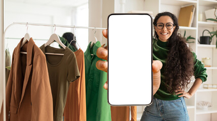 Wall Mural - Fashion App. Stylist Woman Showing Blank Smartphone While Standing Near Clothing Rail