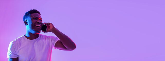 Poster - Happy young black man talking on smartphone in neon light, banner design with empty space