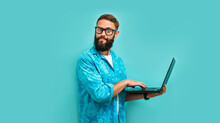 Young Crazy Bearded Charismatic Man. Shocked Or Surprised Expression. Laptop Concept. Funny Promotion Poster. Programmer, Web Developer Holding A Laptop In His Hands And Looking At The Camera