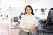 Portrait of female printing office manager standing at printer and looking at camera.