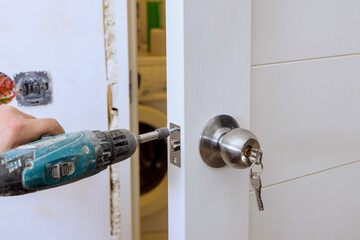 Wall Mural - Builder in installing a door lock the door of a new house hand close-up.